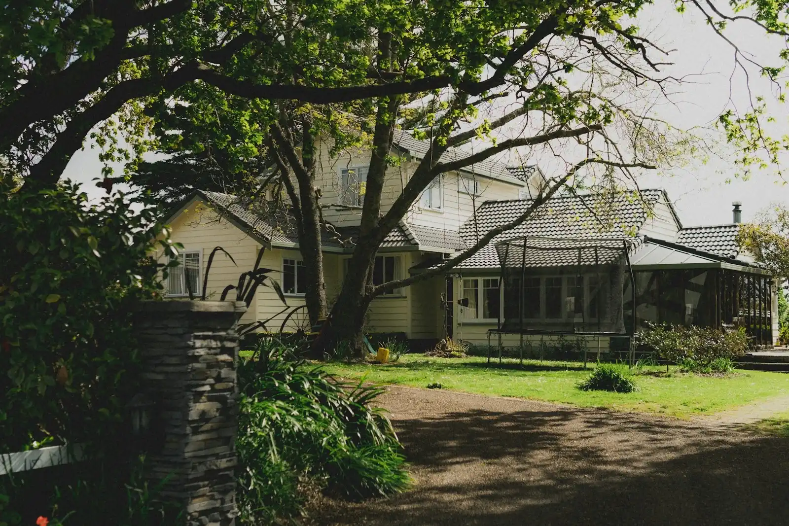 A weatherboard family home with a tiled roof and established garden in suburban New Zealand